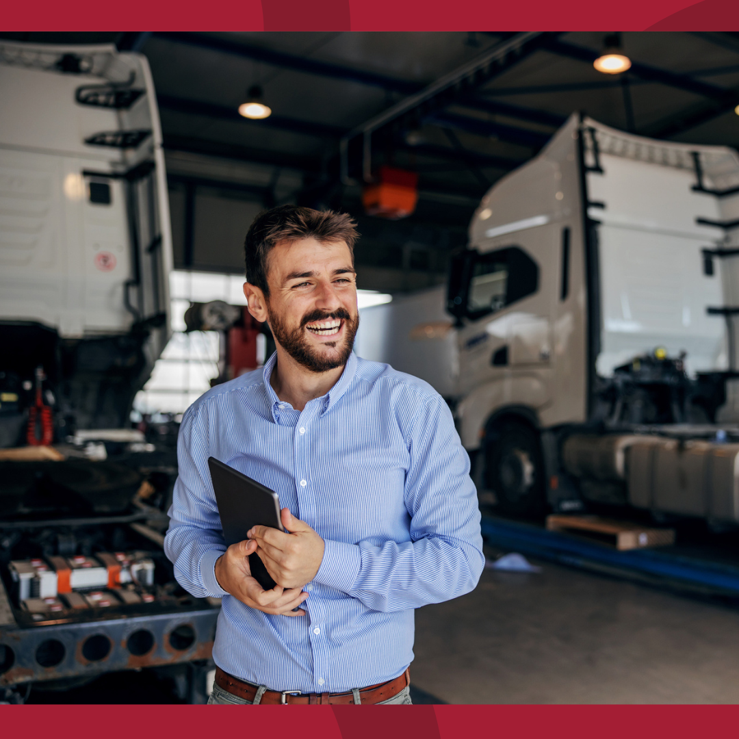 A man holding a tablet in front of two semis.